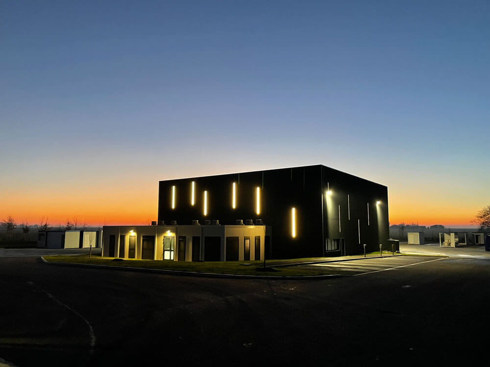 Vue nocturne du bâtiment industriel et des modules Petit Location à Chartres, éclairés sous un ciel au coucher du soleil.